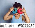 boy is holding two colored doughnuts blue and red in front 65033089