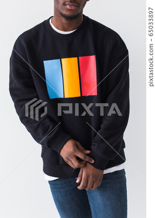Close-up handsome young black man dressed in jeans and sweatshirt on white background. Street fashion and modern youth culture. Close-up handsome young black man dressed in jeans and sweatshirt on white background. Street fashion and modern youth culture. 65033897