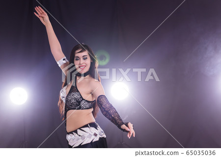 Young woman dancing in Tribal Fusion style. Belly dance on the stage. Young woman dancing in Tribal Fusion style. Belly dance on the stage. 65035036
