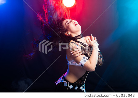 Young woman belly dancer in exotic dress with gold, dancing tribal fusion dance in studio. Young woman belly dancer in exotic dress with gold, dancing tribal fusion dance in studio. 65035048