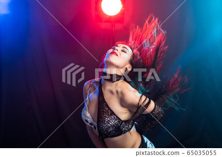 Young woman belly dancer in exotic dress with gold, dancing tribal fusion dance in studio. 65035055