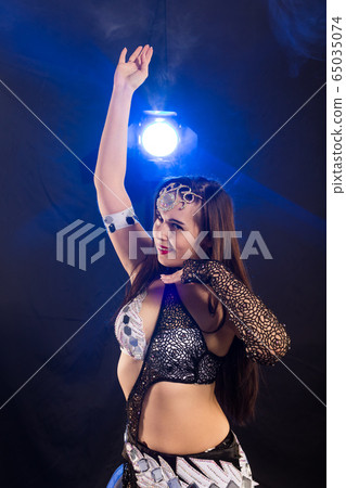 Young woman belly dancer in exotic dress with gold, dancing tribal fusion dance in studio. 65035074