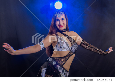 Young woman dancing in Tribal Fusion style. Belly dance on the stage. 65035075