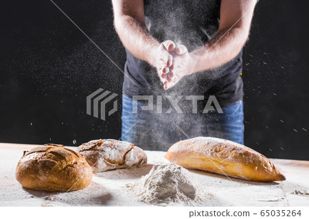 The male hands in flour and rustic organic loaf of bread The male hands in flour and rustic organic loaf of bread 65035264