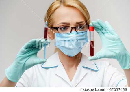 Doctor or woman nurse wearing protective mask holding syringe and blood test tube Doctor or woman nurse wearing protective mask holding syringe and blood test tube 65037466
