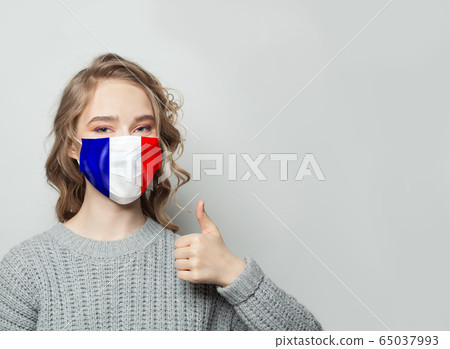 Happy woman in face mask holding thumb up  65037993