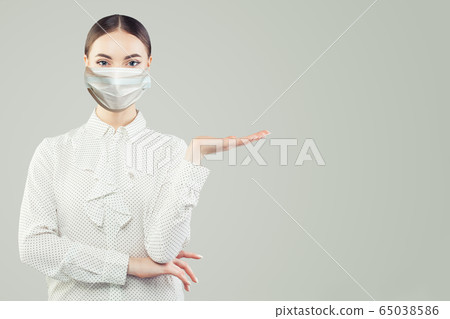 Smart woman in face mask showing empty open hand Smart woman in face mask showing empty open hand 65038586