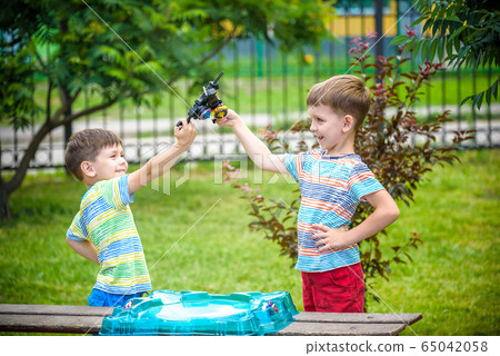 Two boys playing with a spinning top kid toy. 65042058