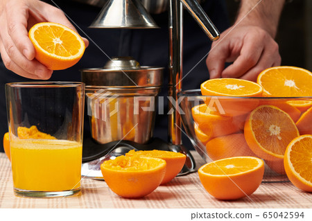 Squeezing an orange with a manual press, close 65042594