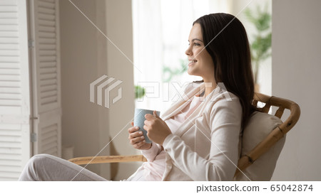 Happy woman relax in chair enjoy coffee or tea 65042874