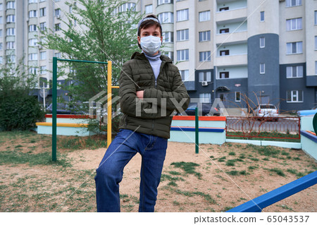 teen boy stands by seesaw on playground near teen boy stands by seesaw on playground near 65043537