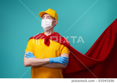 Courier is wearing in superhero cloak and protected face mask. Courier is wearing in superhero cloak and protected face mask. 65045896