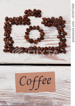 Coffee beans on the table arranged in a shape of photo camera. 65047888