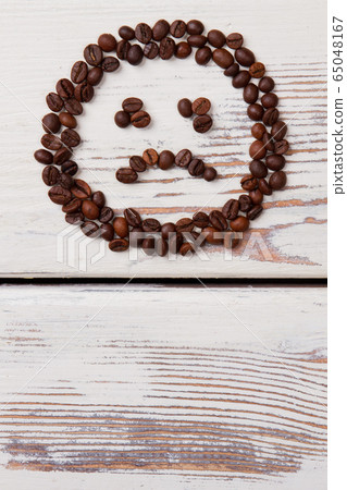 Unhappy smiley face made of coffee beans. Unhappy smiley face made of coffee beans. 65048167