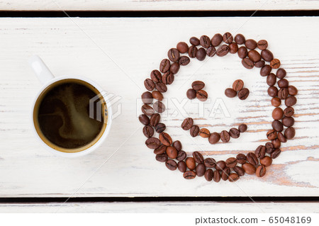 Top view cup of hot coffee and beans in a shape of smiley face. 65048169