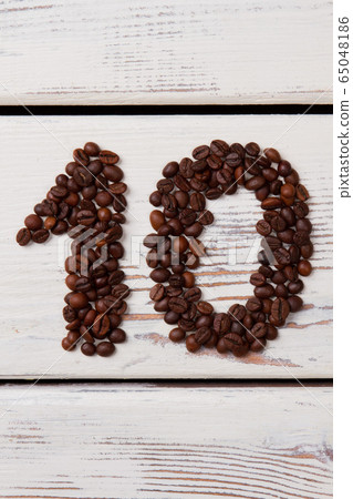 Brown coffee beans arranged in a shape of number ten. Brown coffee beans arranged in a shape of number ten. 65048186