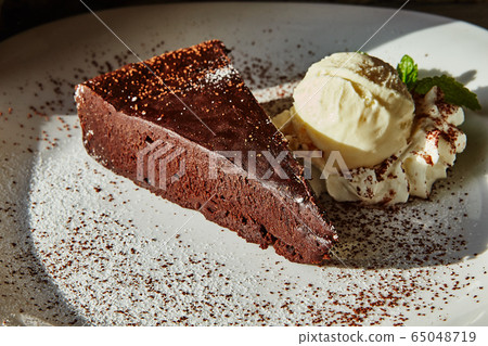 A piece of brownie cake and ice cream on a plate A piece of brownie cake and ice cream on a plate 65048719