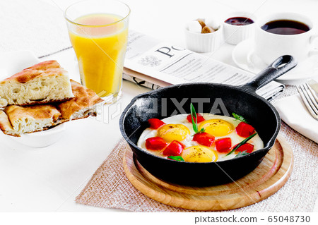 A plate of fried eggs with vegetables and a cup of coffee and juice A plate of fried eggs with vegetables and a cup of coffee and juice 65048730