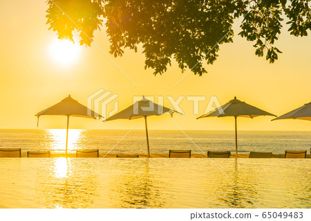 Beautiful tropical outdoor beach sea ocean with umbrella and chiar around outdoor swimming pool at sunset or sunrise time Beautiful tropical outdoor beach sea ocean with umbrella and chiar around outdoor swimming pool at sunset or sunrise time 65049483