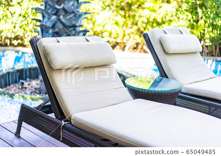Empty chair deck lounge around swimming pool in hotel resort 65049485
