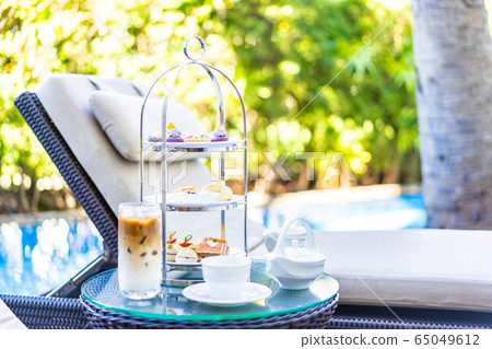 Afternoon tea set with latte coffee and hot tea on table neary chair around swimming pool Afternoon tea set with latte coffee and hot tea on table neary chair around swimming pool 65049612