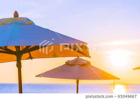 Beautiful tropical nature umbrella chair with palm tree around beach sea ocean at sunset or sunrise 65049667