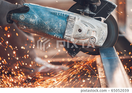 Construction worker using Angle Grinder cutting Metal at construction site. 65052039
