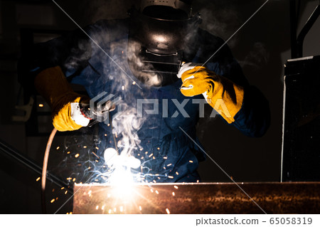 Metal welder working with arc welding machine. Metal welder working with arc welding machine. 65058319