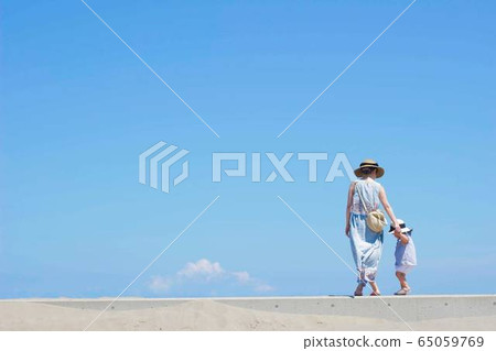 Parent and child walking along the breakwater 65059769