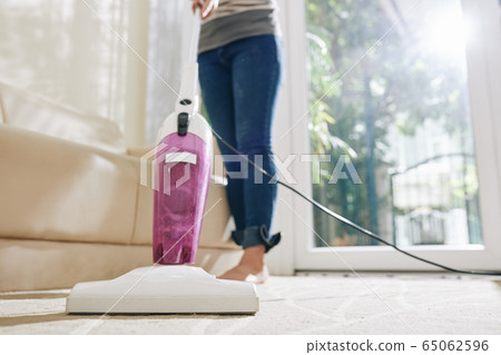 Housewife vacuum cleaning carpet 65062596