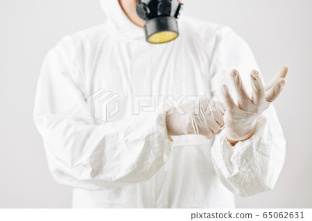 Worker putting on hazmat suit and protective gloves 65062631