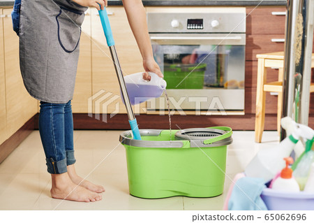 Housewife pouring floor cleaning liquid 65062696