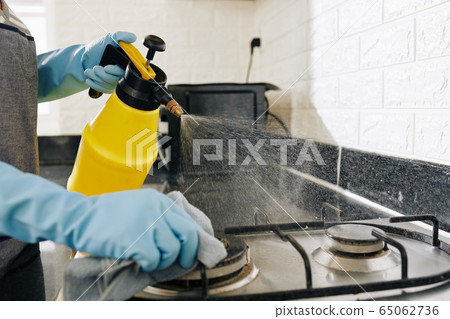Housewife cleaning kitchen stove 65062736