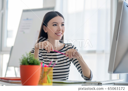 Dark-haired pretty woman in a striped shirt looking happy Dark-haired pretty woman in a striped shirt looking happy 65063172