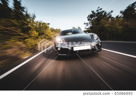 Black sport car speed drive on the autobahn across forest, front lights on Black sport car speed drive on the autobahn across forest, front lights on 65066893