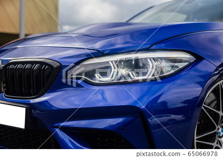 Parking blue sedan outdoor, front light and bumper view 65066978