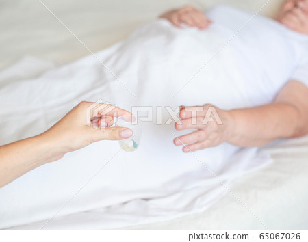 The doctor holds out an elderly woman a pill for dizziness. Woman lying on bed, concept of treating illness with pills, bed rest, copy space The doctor holds out an elderly woman a pill for dizziness. Woman lying on bed, concept of treating illness with pills, bed rest, copy space 65067026