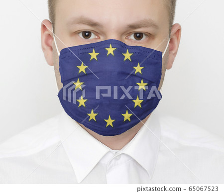 A man in a protective mask on his face with the flag of European Union. The concept of coronavirus and viral infections in the country, portrait A man in a protective mask on his face with the flag of European Union. The concept of coronavirus and viral infections in the country, portrait 65067523