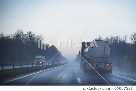 A truck wagon rides on a motorway in fog and rain. The concept of poor visibility on the road, copy space A truck wagon rides on a motorway in fog and rain. The concept of poor visibility on the road, copy space 65067551