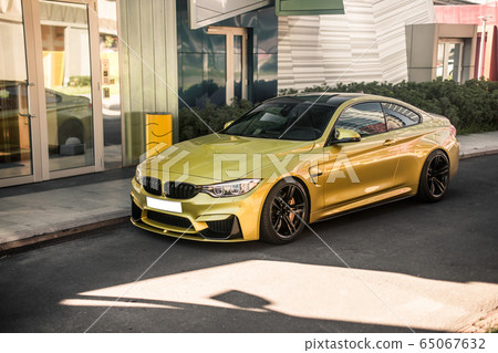 Golden color luxury car, parked in front of an office Golden color luxury car, parked in front of an office 65067632
