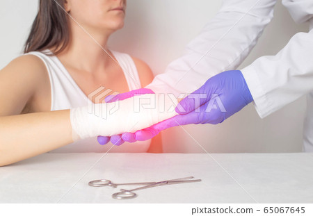 A surgeon doctor examines a patient s palm for a fracture or crack in a bone. Scaphoid fracture, red A surgeon doctor examines a patient s palm for a fracture or crack in a bone. Scaphoid fracture, red 65067645