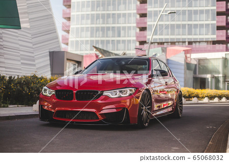 Red model sedan in the landmark parking, across business residences, front view Red model sedan in the landmark parking, across business residences, front view 65068032