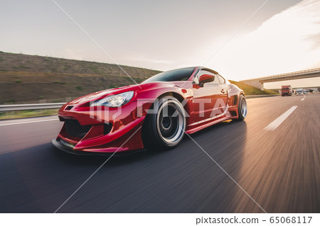 Red racing car on the highway in a sunny day, design lights and wheels Red racing car on the highway in a sunny day, design lights and wheels 65068117