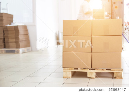 Boxes on a pallet with finished products of sunflower oil on the background of a production workshop with equipment, copy space, business 65068447