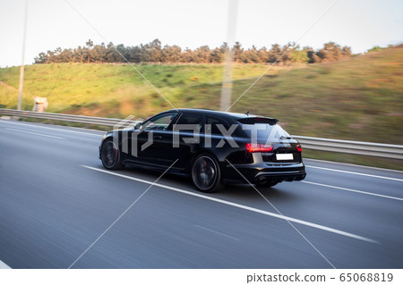 Black hatchback driving in the hills 65068819