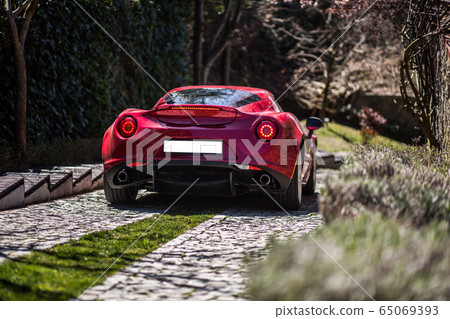Red supercar in the parking in a luxury garden 65069393