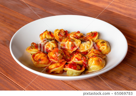 Russian traditional dish pelmeni, meat dumplings with tomato sauce, on white plat, wooden background. Russian traditional dish pelmeni, meat dumplings with tomato sauce, on white plat, wooden background. 65069783