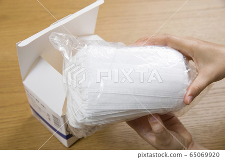 Female hand to take out the mask from the box and check 65069920