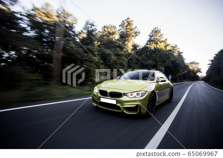 Green sedan landscape drive in the dusk time under dark clouds in the forest, front view Green sedan landscape drive in the dusk time under dark clouds in the forest, front view 65069967