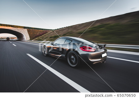 Navy blue sport car speed drive on the autobahn in the sunset, view from behind Navy blue sport car speed drive on the autobahn in the sunset, view from behind 65070650